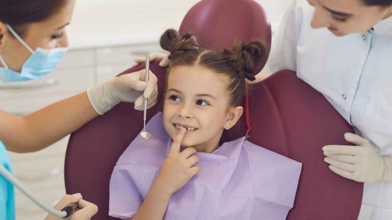 Child smiling at dentist chair during oral checkup with modern tools, showing advances in dentistry and dental technology.