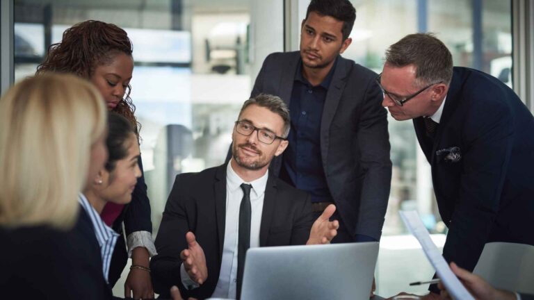 Business professionals in formal suits discussing at a meeting, representing a proper business attire dress code.