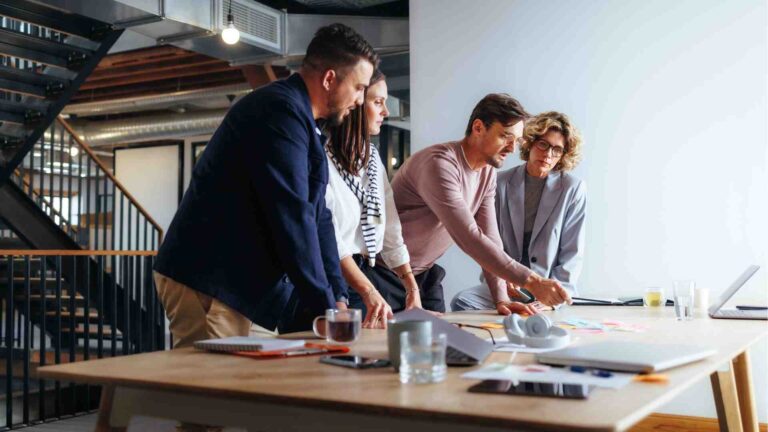 Business team collaborating at a modern office, discussing ideas in professional attire with a black business dress style inspiration.