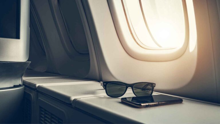 Luxury travel essentials on window seat in Air Serbia Business Class cabin, showcasing comfort and premium experience.