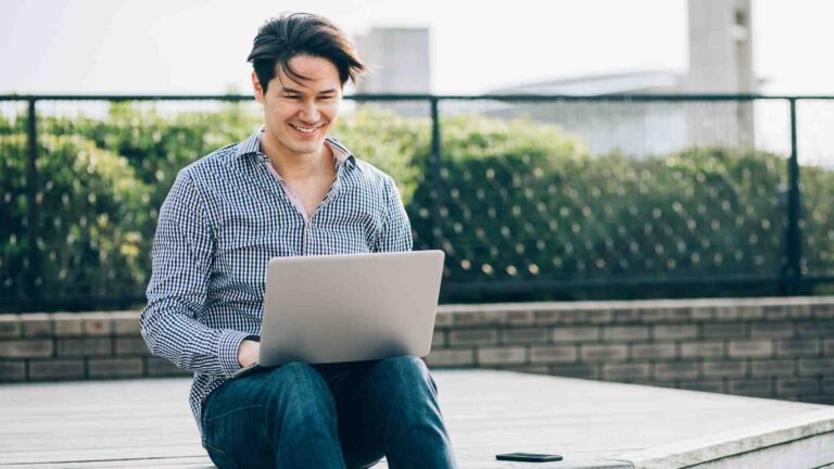 Man using a laptop outdoors as one of the modern examples of technology in daily life.