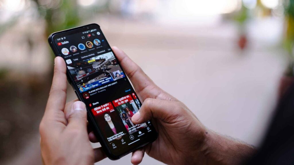 Person using smartphone YouTube app, ideal for Mp4 Download Youtube tools and apps in 2025.