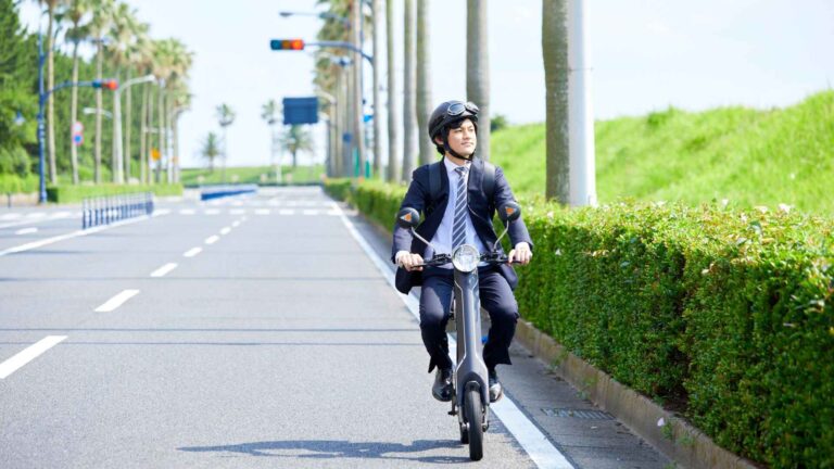 Businessman riding an electric bike to work using an electric bike charger-powered e-bike on a sunny city road