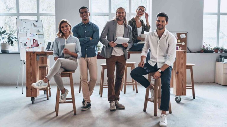 Group of teens in business casual outfits smiling confidently in a modern office setting