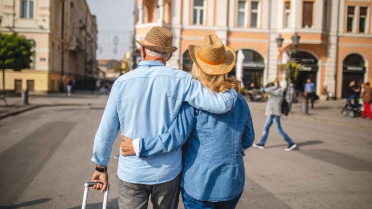 Senior couple enjoying a vacation with A&A Travel, walking together in a scenic city street.